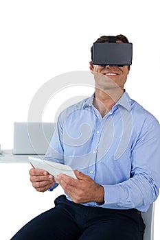 Smiling businessman holding tablet while wearing vr glasses