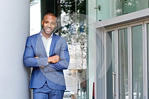 Smiling businessman leaning against wall outdoors