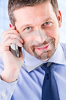 Smiling businessman making a phone call.