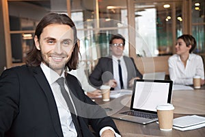 Smiling businessman manager in suit looking at camera at meeting