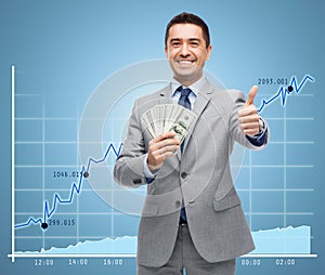 Smiling businessman with money showing thumbs up