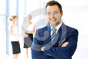 Smiling businessman in office with colleagues in the background