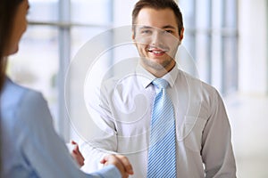 Smiling businessman in office is shaking hands with his partner