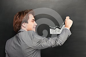 Smiling businessman painting graph on chalkboard