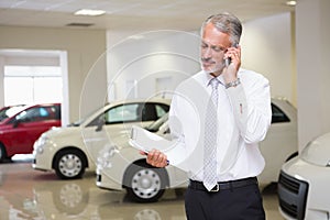 Smiling businessman on the phone holding clipboard