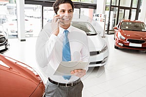 Smiling businessman on the phone holding clipboard