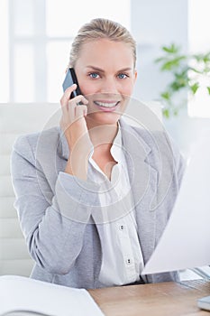 Smiling businessman phoning at her desk