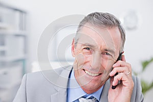 Smiling businessman phoning at his desk