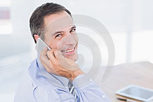 Smiling businessman phoning at his desk