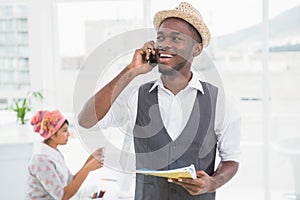 Smiling businessman phoning and holding notebook