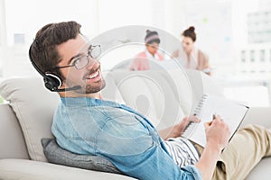 Smiling businessman phoning and taking notes on sofa