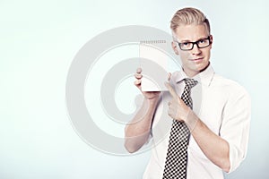 Smiling businessman pointing finger at blank notebook.