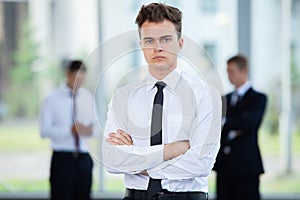 Smiling Businessman posing while colleagues talking together in office.