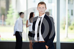 Smiling Businessman posing while colleagues talking together in office.