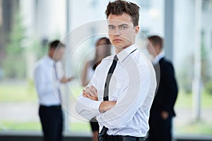 Smiling Businessman posing while colleagues talking together in office.