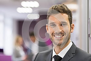 Smiling Businessman posing while colleagues talking together in photo