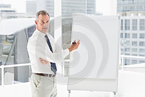 Smiling businessman presenting at whiteboard with marker