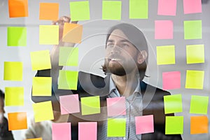 Smiling businessman reading tasks on sticky papers, post it notes
