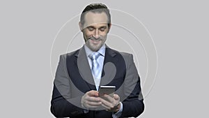 Smiling businessman received message on smartphone.