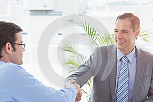 Smiling businessman shaking hands with a co worker