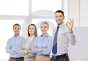 Smiling businessman showing ok-sign in office