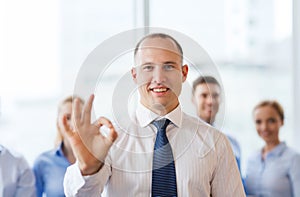 Smiling businessman showing ok sign in office