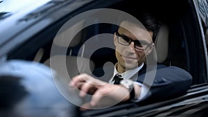 Smiling businessman sitting in car, looking at rear view mirror, testing car