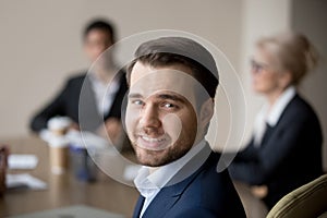 Smiling businessman sitting at the desk in office looking camera