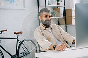 Smiling businessman sitting in modern office and looking