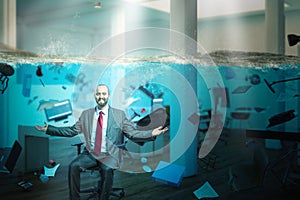 Smiling businessman sitting in an office completely flooded