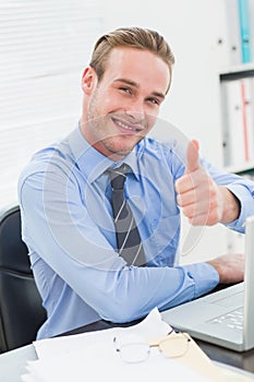 Smiling businessman sitting with thumb up
