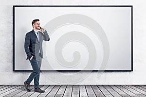 Smiling businessman with smartphone, whiteboard