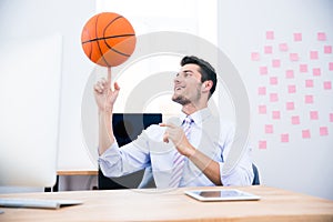 Smiling businessman spining ball in office