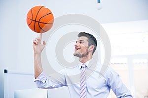 Smiling businessman spining ball in office