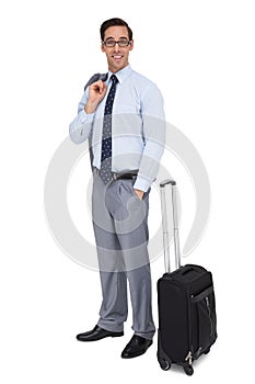 Smiling businessman standing next to his luggage
