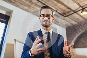 Smiling businessman while standing in the office and looking at camera