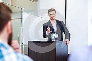Smiling businessman standing at tribune in conference hall