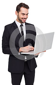 Smiling businessman standing and using laptop