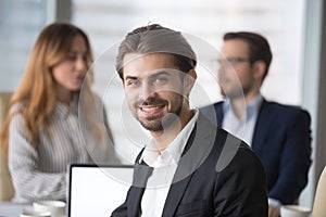 Smiling businessman in suit looking at camera posing at meeting