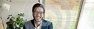 Smiling businessman in suit working with documents from home office and looking at camera