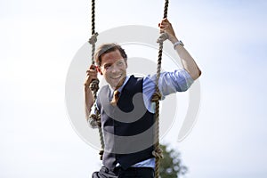 Smiling businessman swinging in ropes photo