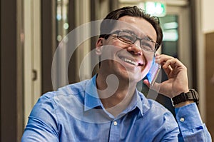 Smiling businessman talking at the cafe. Happy businessman using a mobile phone