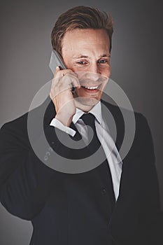 Smiling businessman talking on his cellphone against a gray back