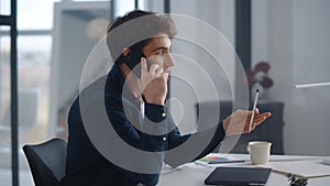 Smiling businessman talking mobile in office. Relaxed business man calling phone