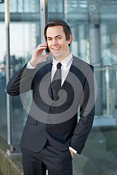 Smiling businessman talking on mobile phone outdoors