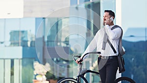 Smiling businessman talking over mobile phone standing with bicycle