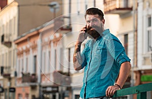 Smiling businessman talking on phone in the city. Business man using smartphone on the street. Man standing outside a