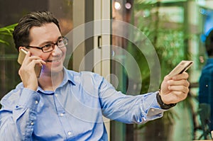 Smiling Businessman talking with smart phone and Giving Card to Waiter in Cafe