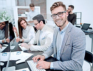 Smiling businessman uses a computer to analyze financial data