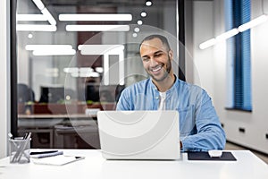 Smiling businessman using laptop in modern office